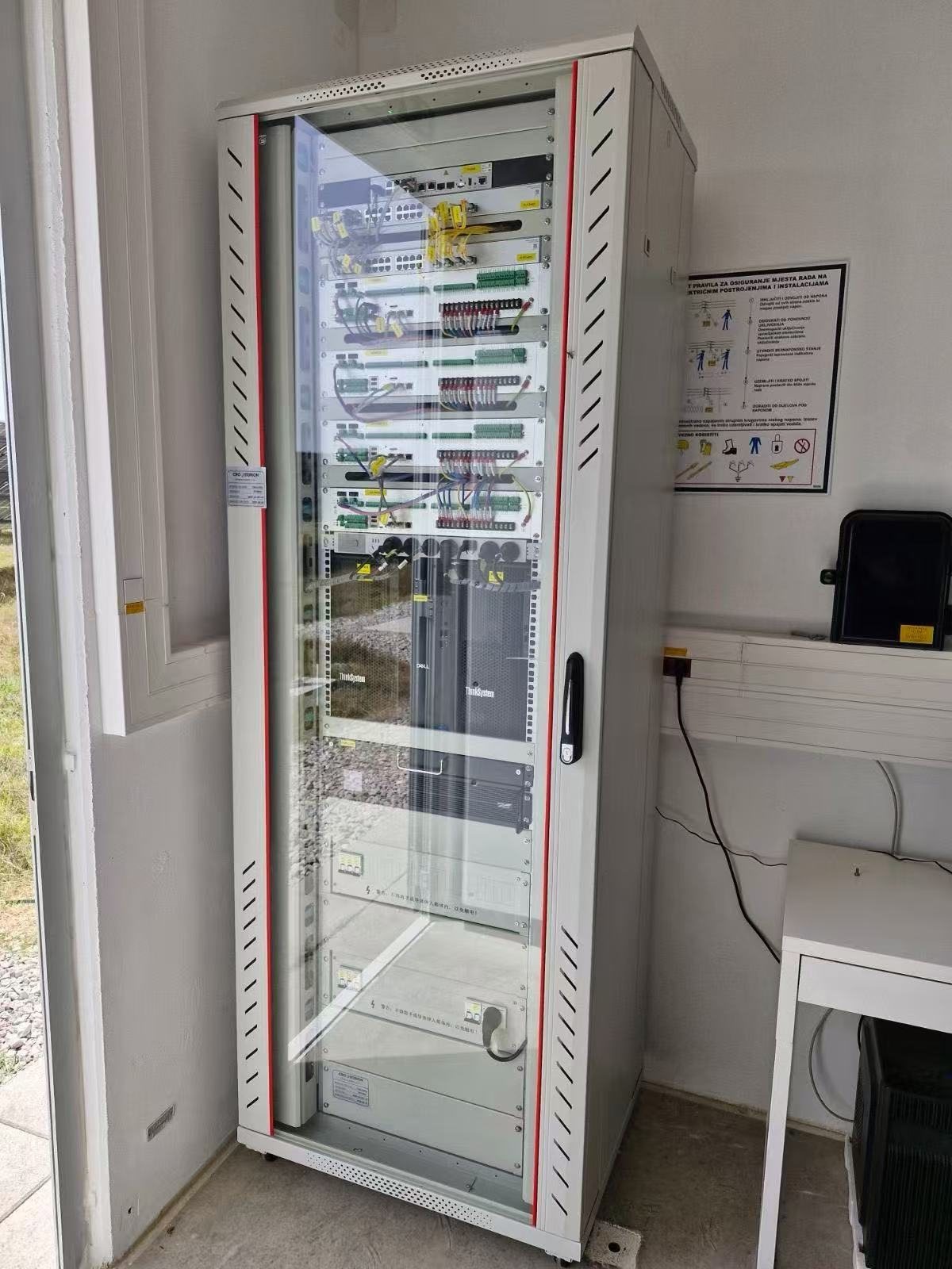 Un rack de control CROSTORION instalado: paneles de parcheo, switches, unidades de control coordinado, servidores y un SAI en un armario con puerta de cristal