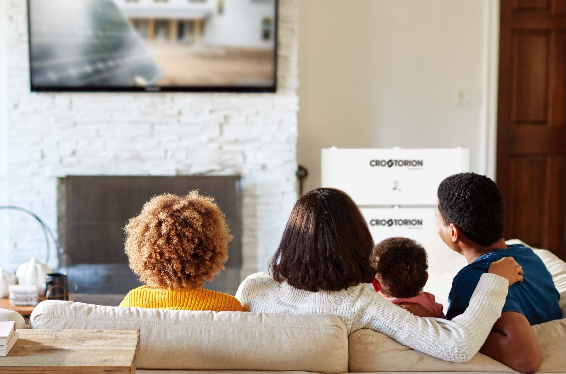 Eine Familie im Wohnzimmer, dahinter der CROSTORION-Heimspeicher an der Wand