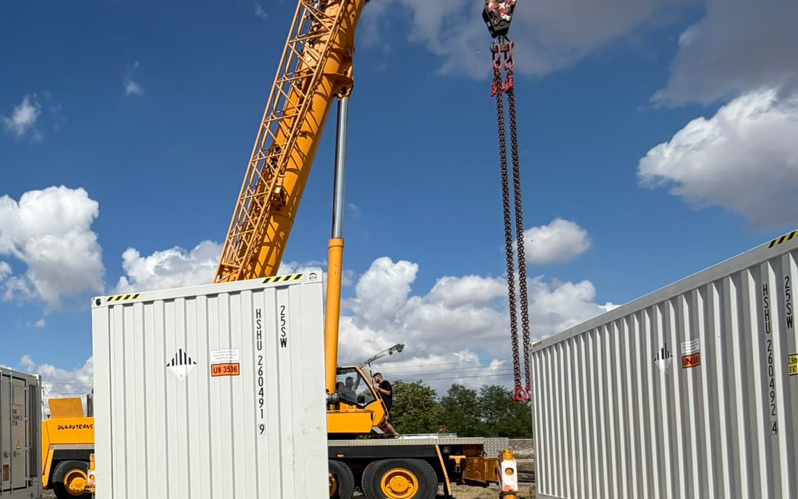 Ein Mobilkran setzt einen Batteriecontainer auf das Fundament in Vođinci